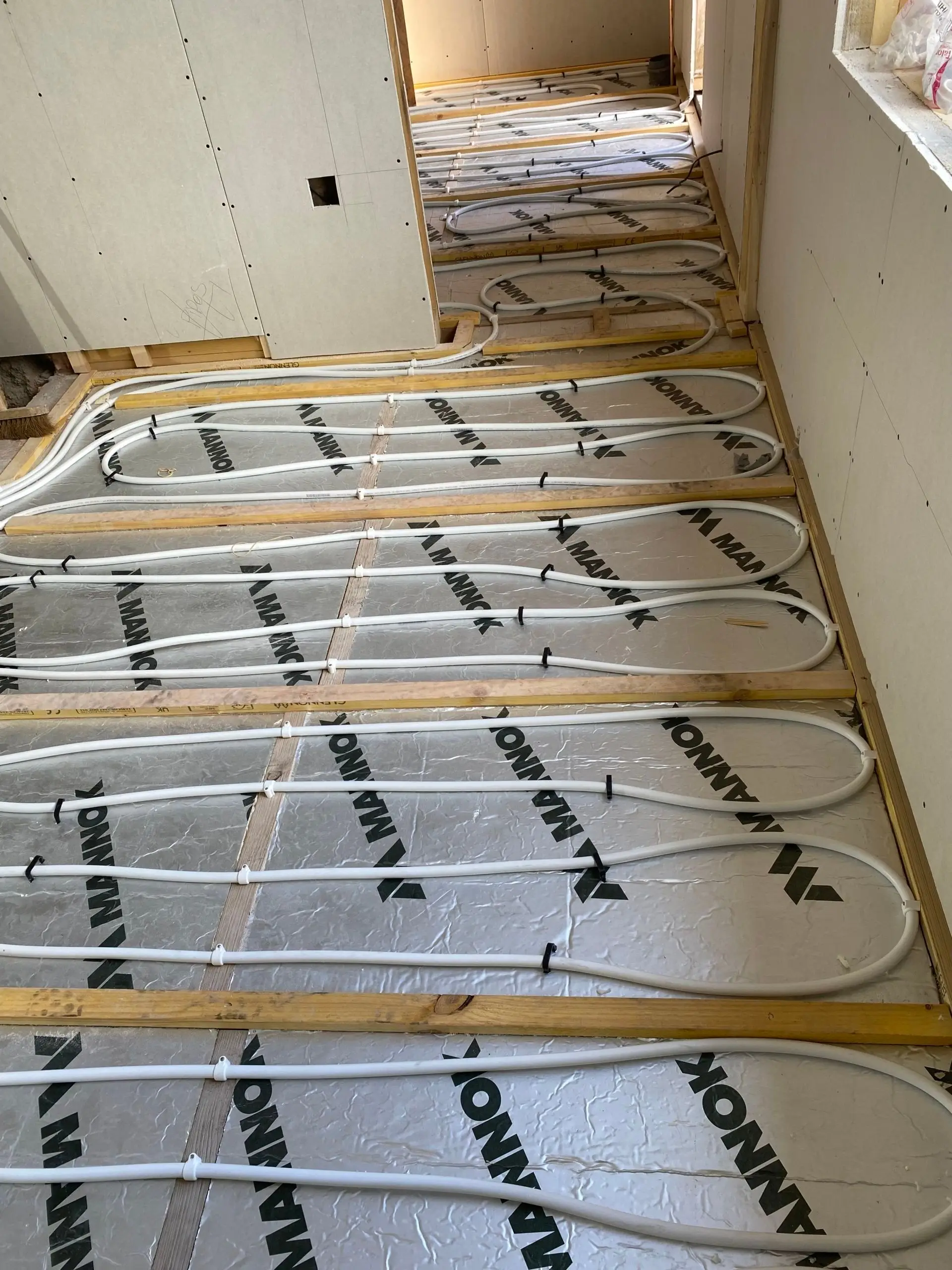 Underfloor heating pipe clipped in runs directly onto insulation boards, before screeding
